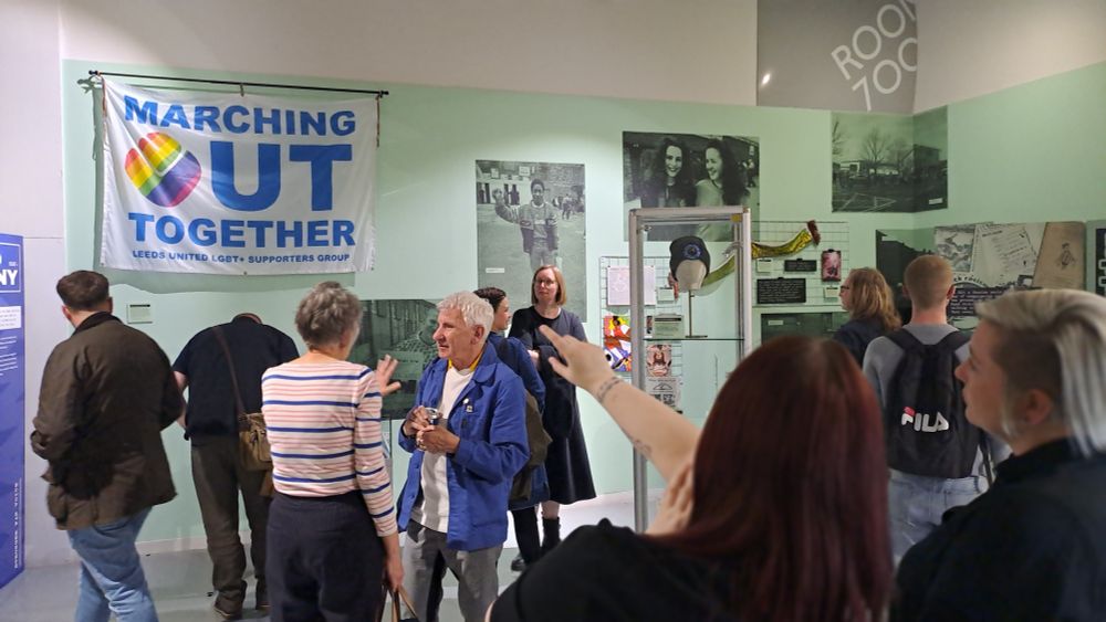 Gallery scene with large MOT banner, guests talking and viewing displays
