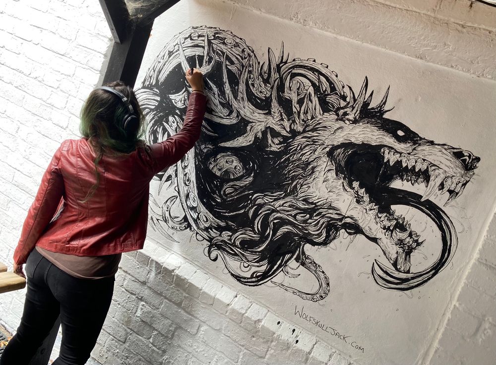 A photo of me drawing a big tentacle wolf head on a wall  