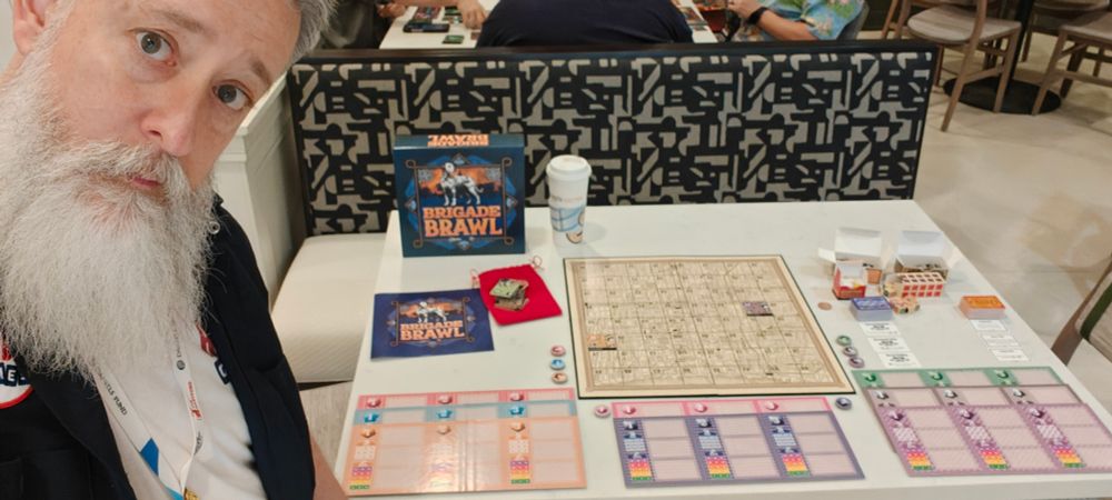 A silly, bearded man stands next to a game called Brigade Brawl by Risible Games.