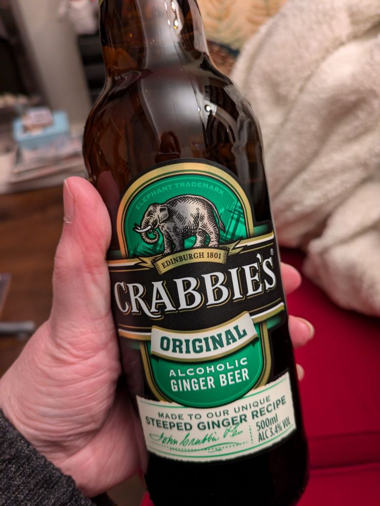 My hand holding a bottle of Crabbies alcoholic ginger beer, nectar of the gods