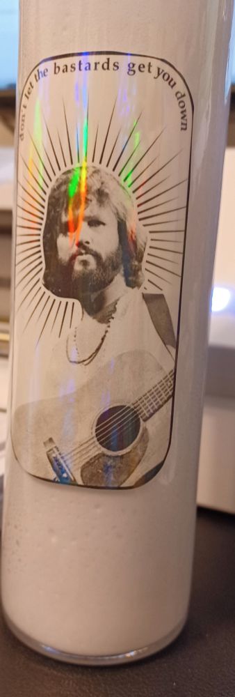 don't let the bastards get you down sticker w/ halo'd kris kristofferson, holographic on a dollar store prayer candle