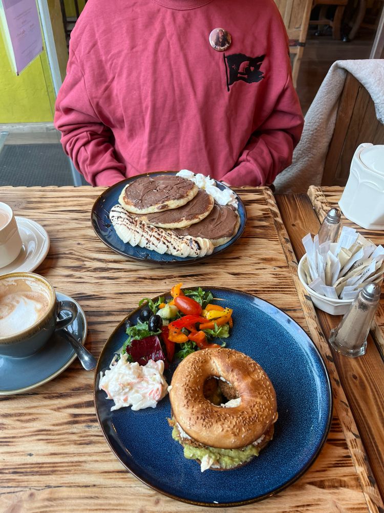 plate with a bagel and salad, and tuka’s plate with nutella banana pancakes and their cute depression robe inspired jumper