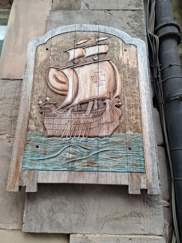 Wooden  carving of medieval galleon. The wooden  plauge is on the side of building on Maratime St Leith Edinburgh 