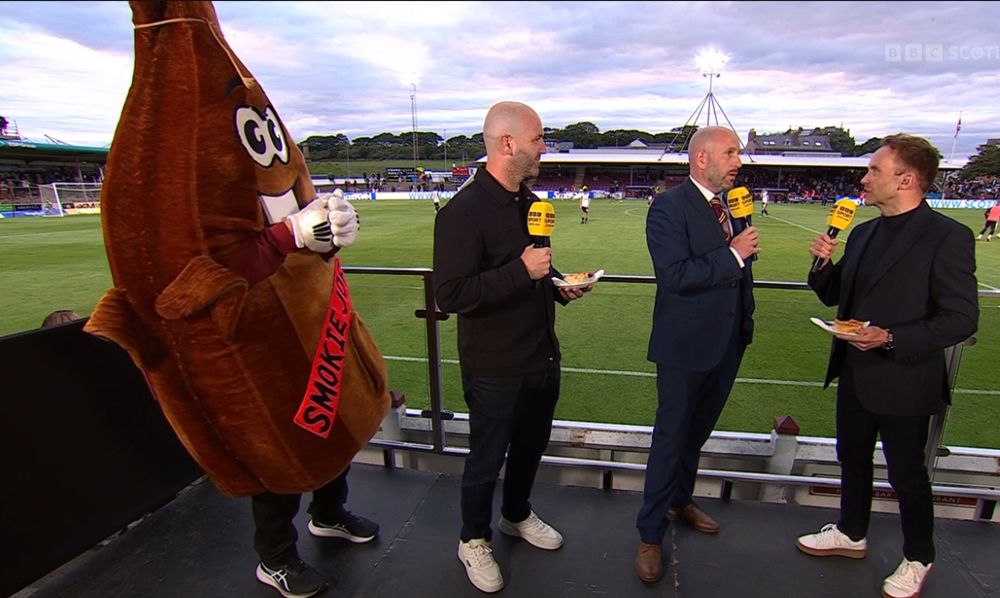 Arbroath mascot dressed in smoked haddock costume stands next to BBC Football presenters and the CEO of Arbroath FC. 