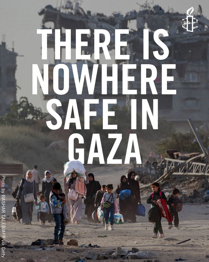 Image shows people displaced by conflict and fleeing from Beit Hanun in the northern Gaza Strip arrive carrying their belongings in Gaza City with the words "There is nowhere safe in Gaza" written