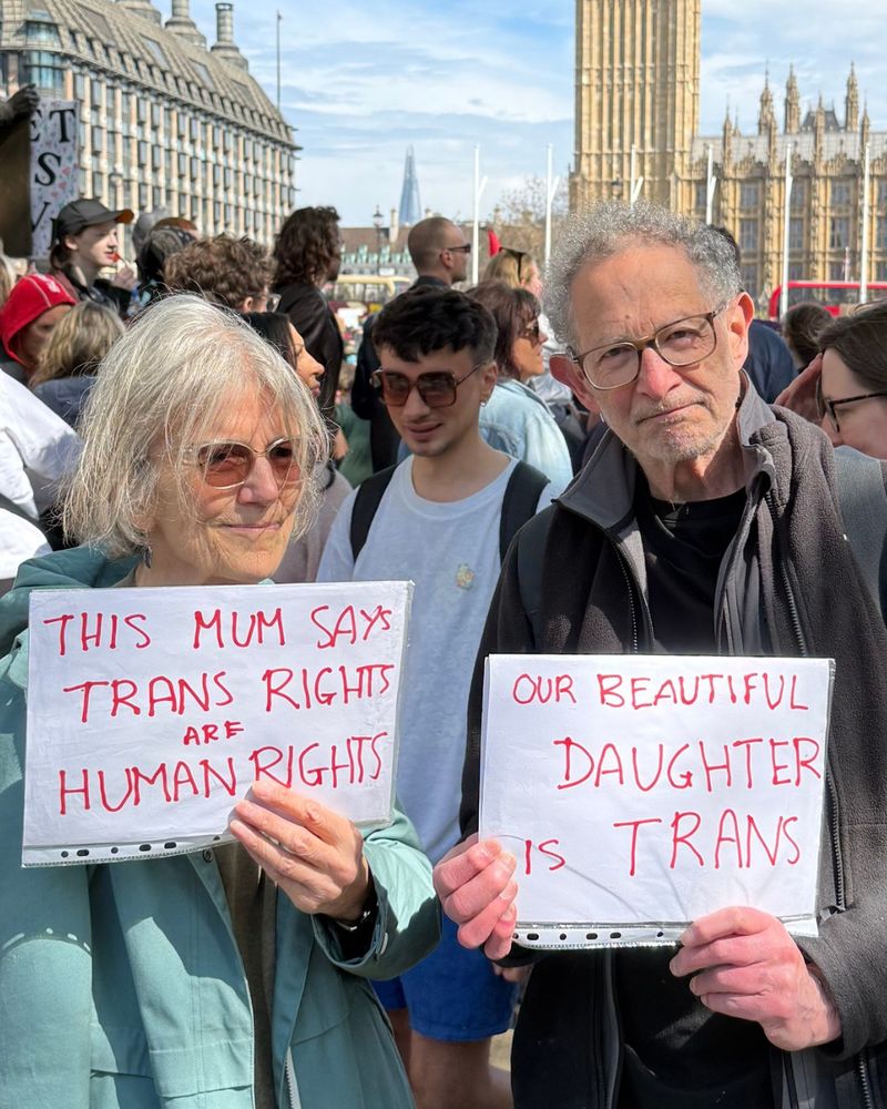 Parents holding up a sign saying: "this mum says trans rights are human rights" and "our beautiful daughter is trans."