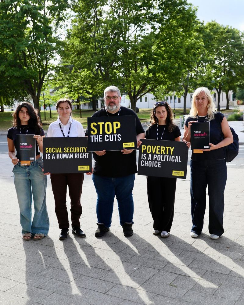 Five people holding placards and the Amnesty Social Insecurity report. The placards read: social security is a human right, stop the cuts and poverty is a political choice. 