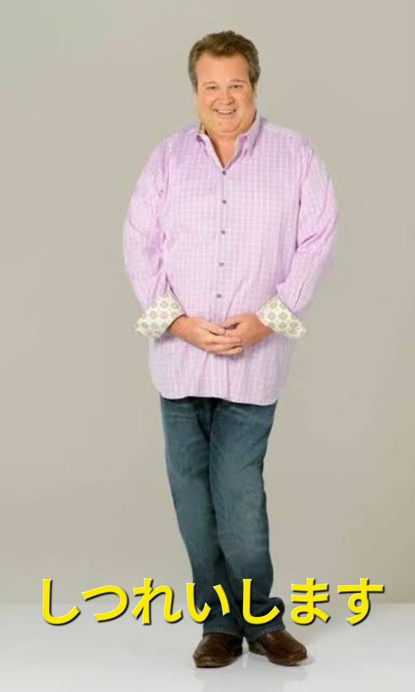 Fotografia do personagem Cameron Tucker da série "Modern Family", interpretado por Eric Stonestreet. Homem gordo com cabelos castanhos, rosto redondo, utilizando uma camiseta social rosa listrada com mangas em detalhes amarelhos e brancos, calça jeans e sapatos marrons. Ele está fazendo uma pose em que segura as mãos na altura do umbigo e curva levemente uma das pernas ao mesmo tempo que faz um sorriso bem simpático. Abaixo, escrito em letras amarelas "しつれいします" (lê-se "shitsureishimasu"), que signifca "com licença" em japonês.
