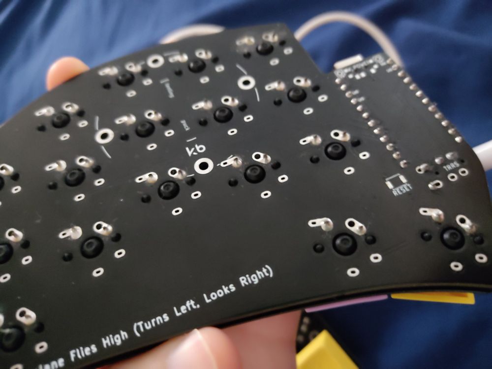 Uma foto mostrando em baixo de uma das metades. É possível ver os pontos de solda das teclas e do chip.