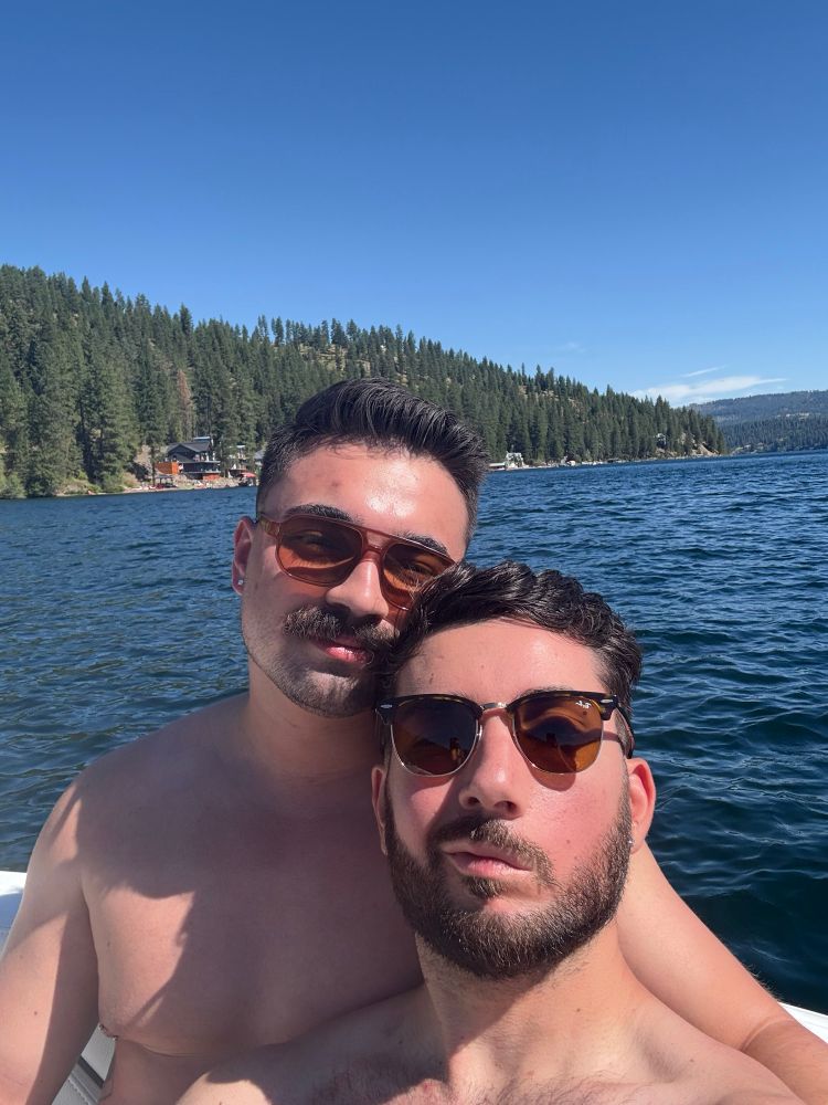 Two young men in sunglasses selfie on a lake 