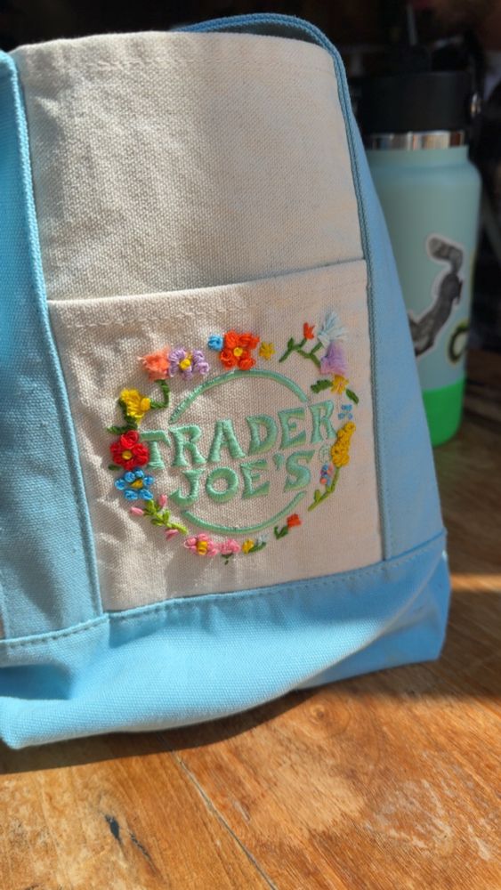 Blue Trader Joe’s mini tote. Embroidered flowers around logo. 