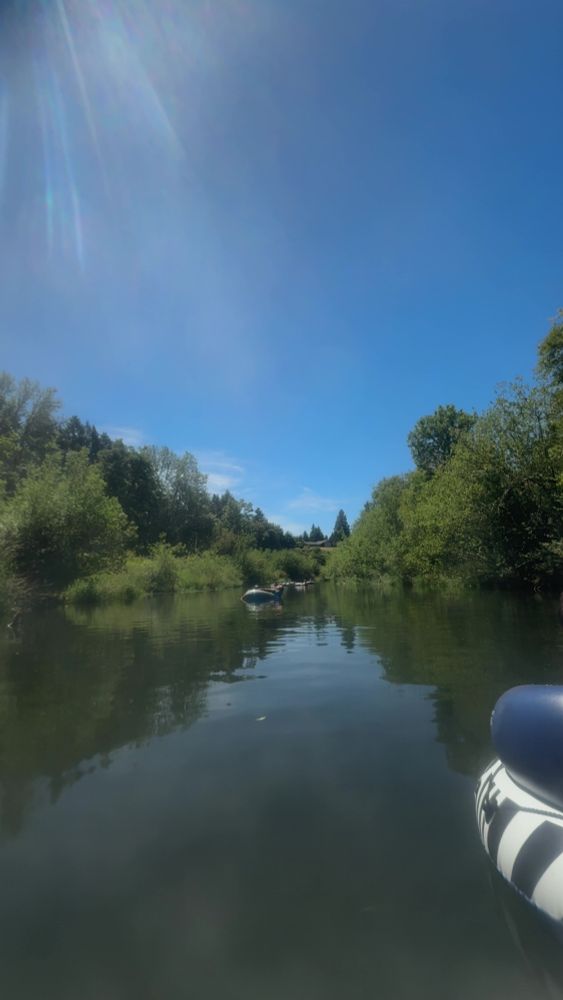 River with trees along banks. People floating on tubes in river 