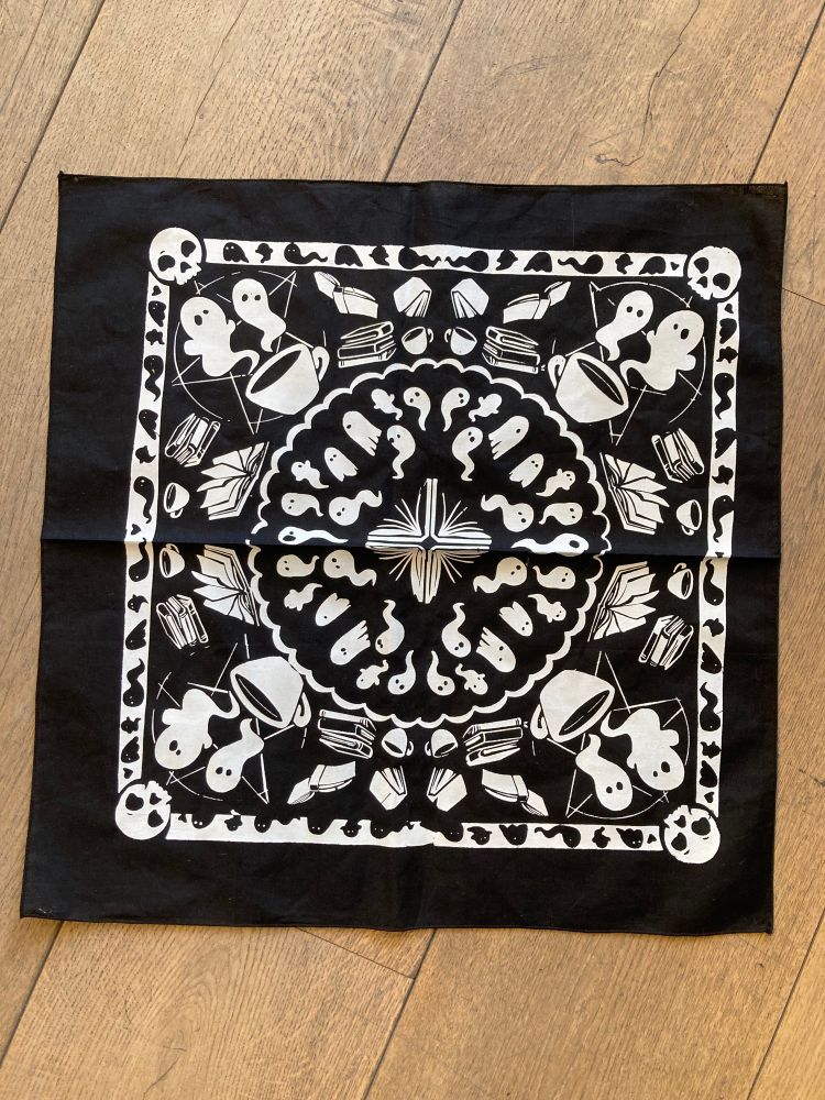 The little black bandanna! Depicts a pattern of our logo with a banner of skulls and ghosts, open books inside, and an interior pattern of a mixture of wiggly and sheet ghosts.