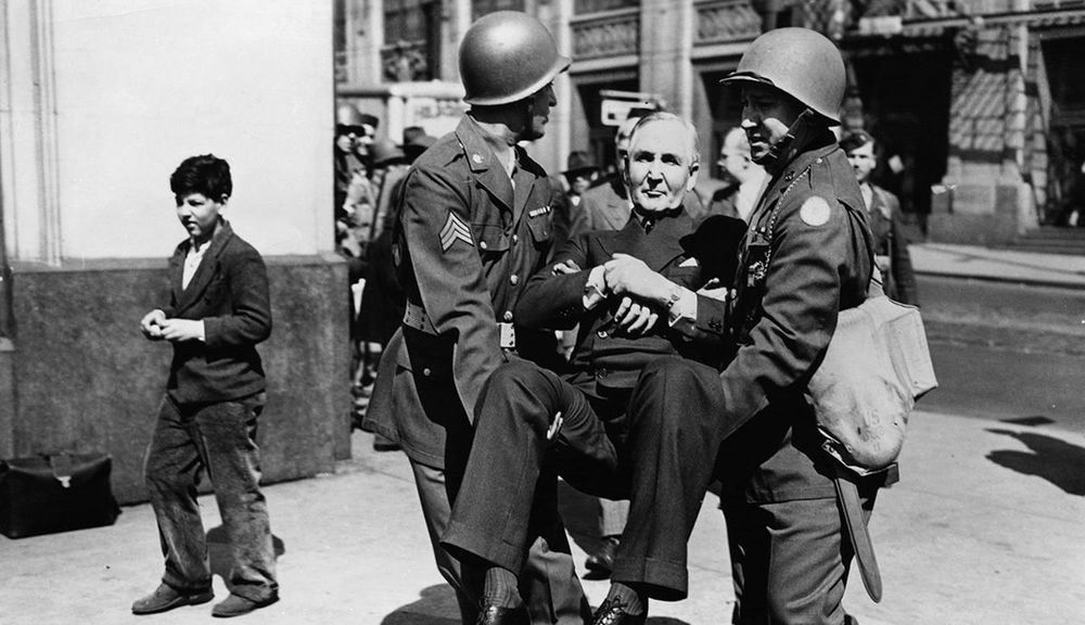 Montgomery Ward head Sewell Avery carried from his office by American soldiers.