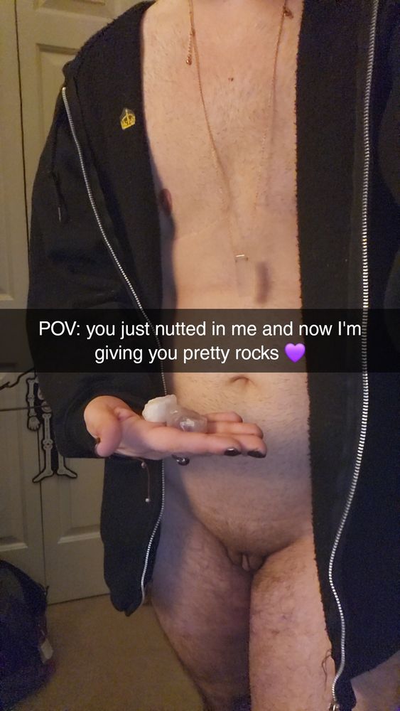 Pic of Rue standing in nothing but a zip hoody, rose quartz necklace around his neck. In his hand is an amethyst and a clear quartz. Snapchat caption over the top reads "POV: you just nutted in me and now I'm giving you pretty rocks💜"