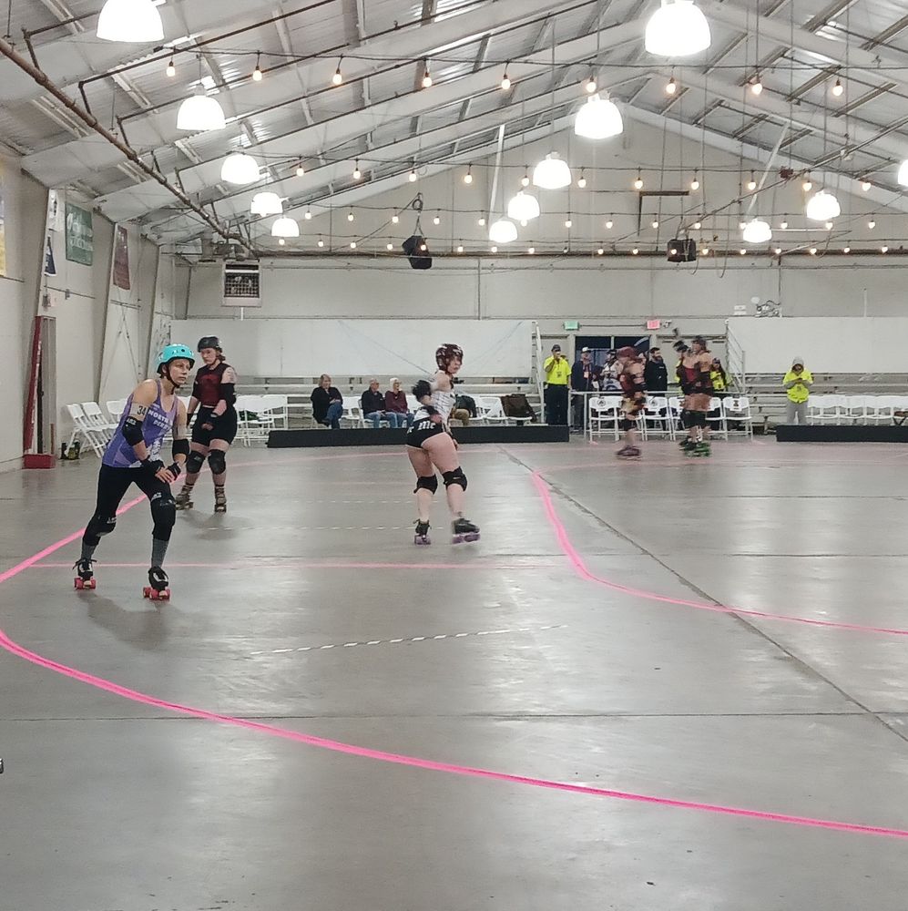 Roller derby skaters warming up. One has booty shorts that say, "Bite me!"