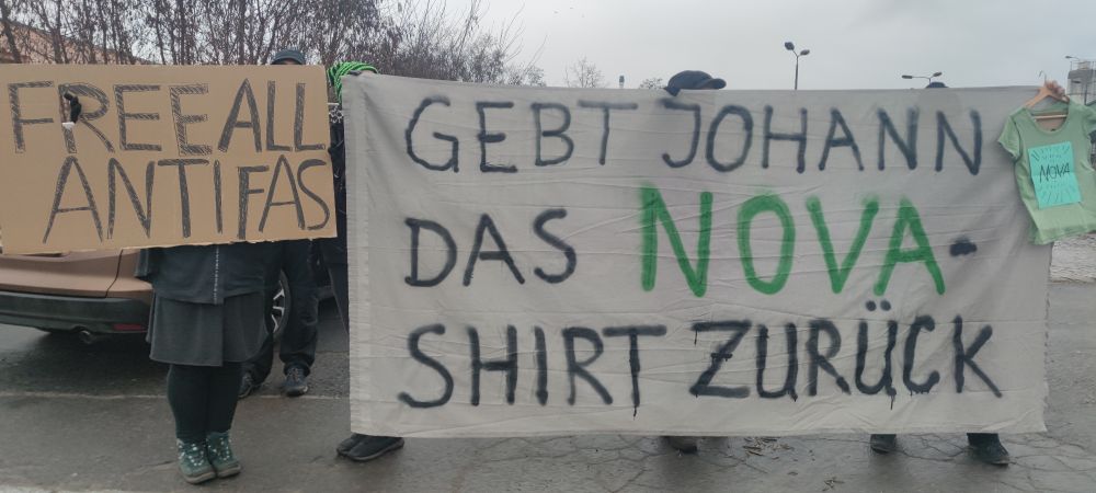 Protestierende mit Transpi Gebt Johann das Nova Shirt zurück und Schild Free all Antifas.