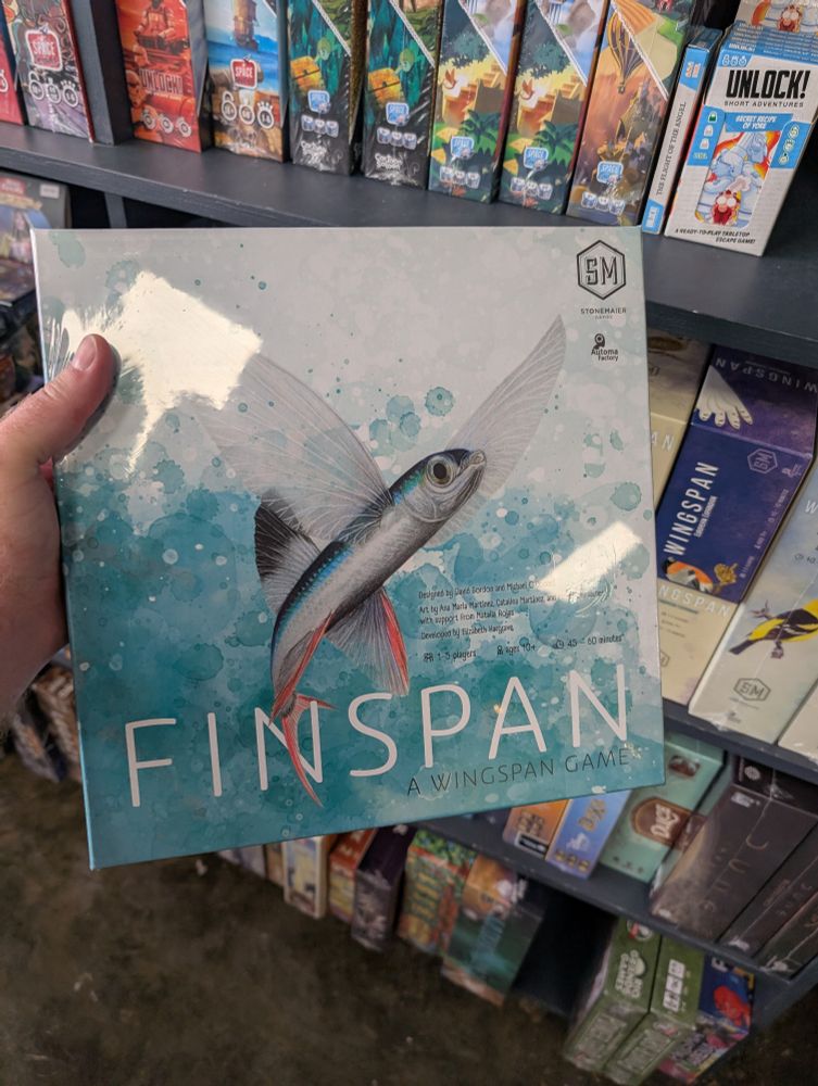 Finspan game held in front of shelf of wingspan.