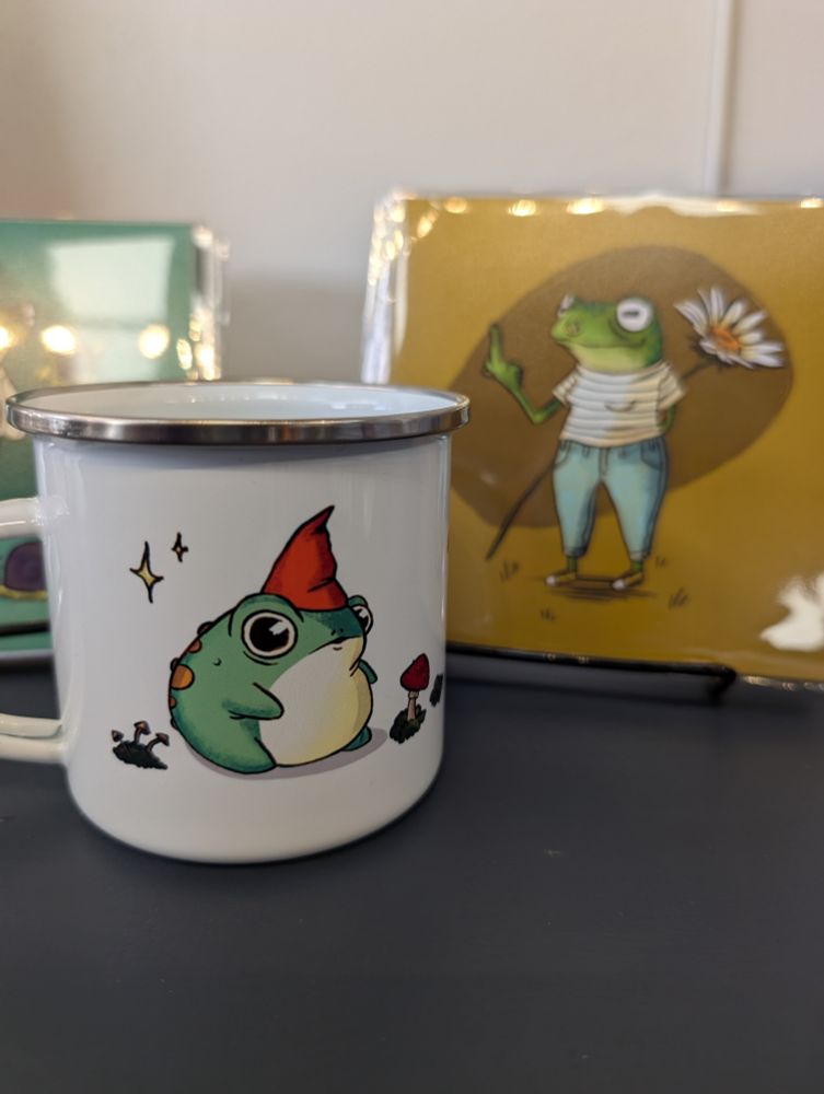 Frog wizard on a mug and frog flipping the bird in background.