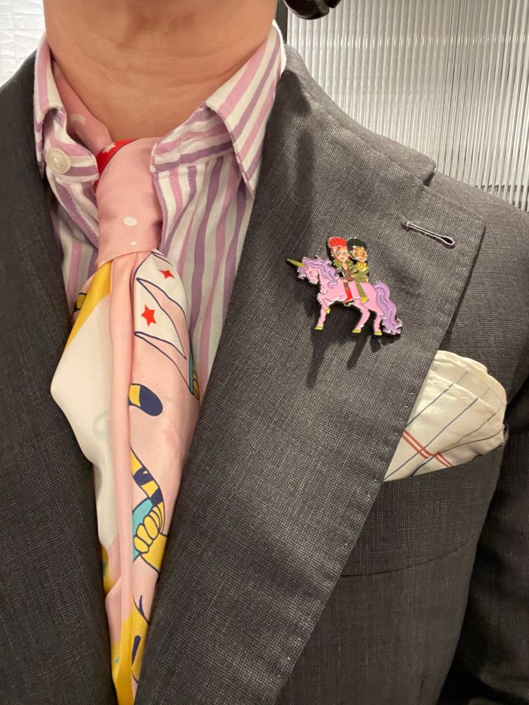 Closeup of the college ruled paper print pocket square; David Bowie with bright red hair and Ziggy Stardust face makeup in front of Prince in a green assless suit on a pink unicorn with a curly purple mane and tail; and a pink silk scarf tied in a half Windsor knot, showing the tail of a tiger.