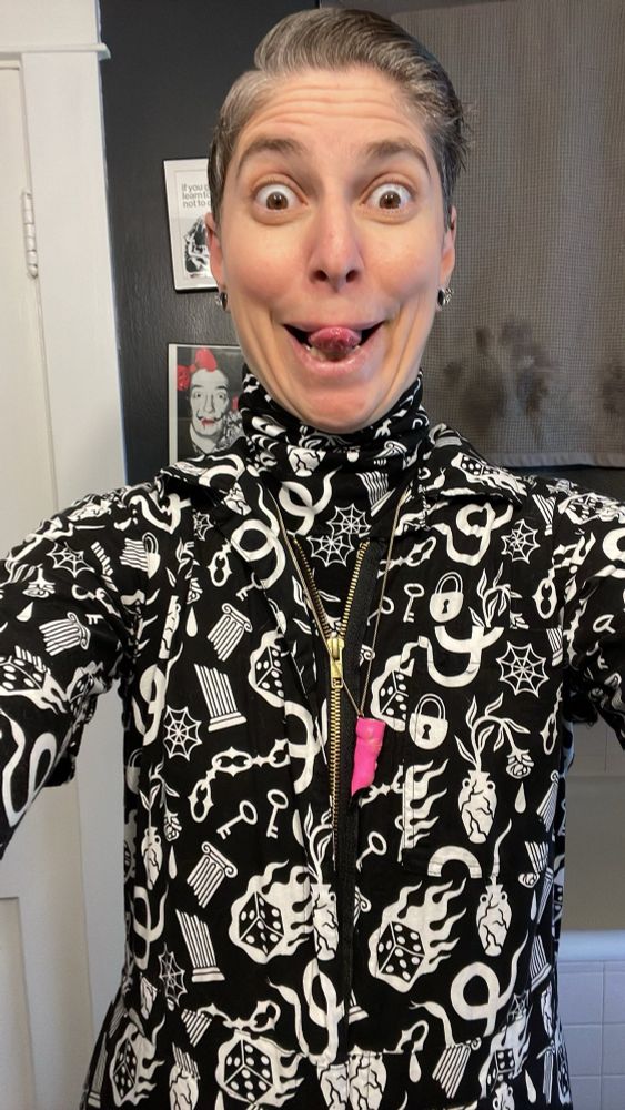 Same outfit just closeup from the waist up; the person has their eyes open wide in an expression of excitement with a big smile and their tongue stuck out.