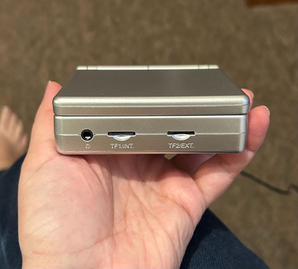 A square silver clamshell gaming console roughly the size of my palm.