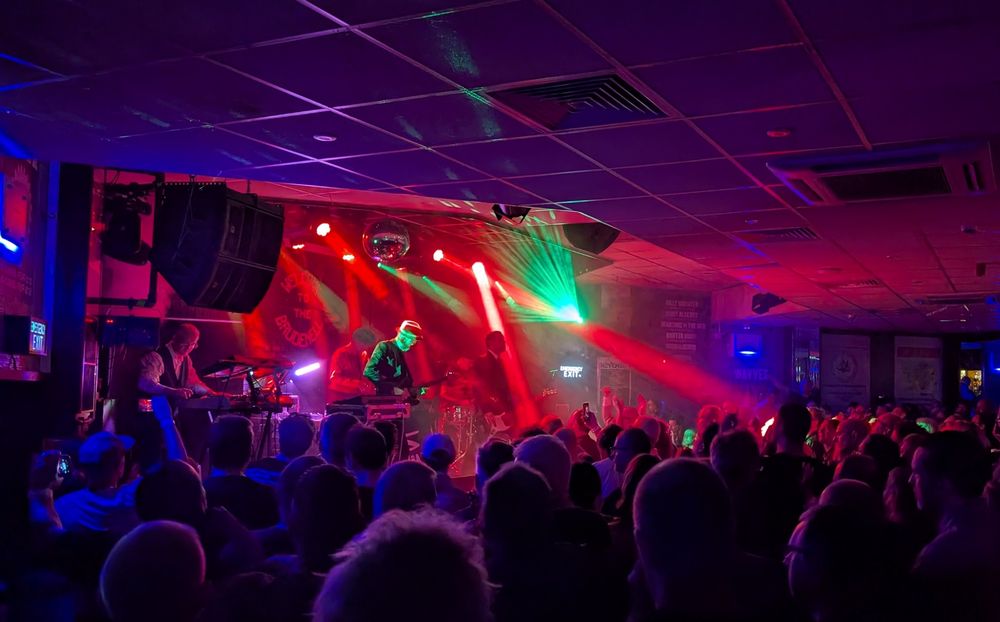 The Sabres Of Paradise on stage at Brudenell Social Club in Leeds, a five piece band in front of a crowd dancing, lights and smoke etc