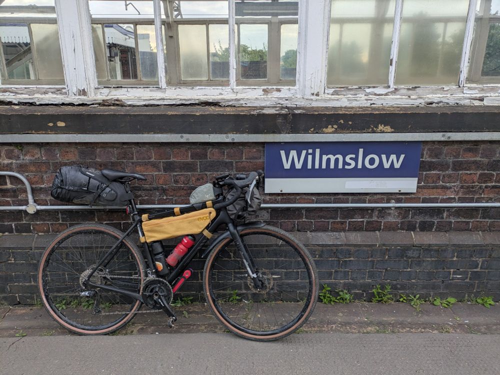 Fully laden bicycle next to Wilmslow station sign