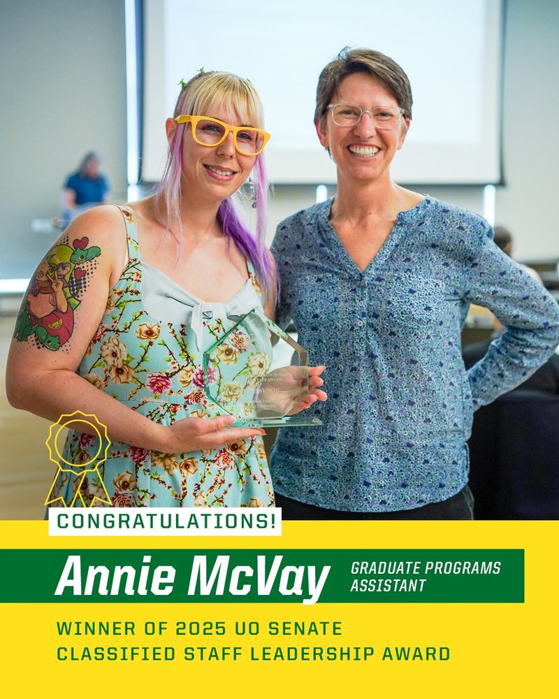 Annie McVay holding an award at the 2025 UO Senate Graduate Programs Classified Staff Leadership Award ceremony, posing with another individual, both smiling in a conference room.