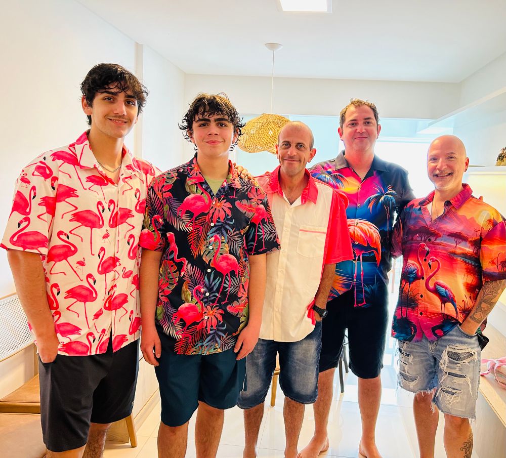 Give guys standing in a row, all wearing shirts from MMS Flamingo