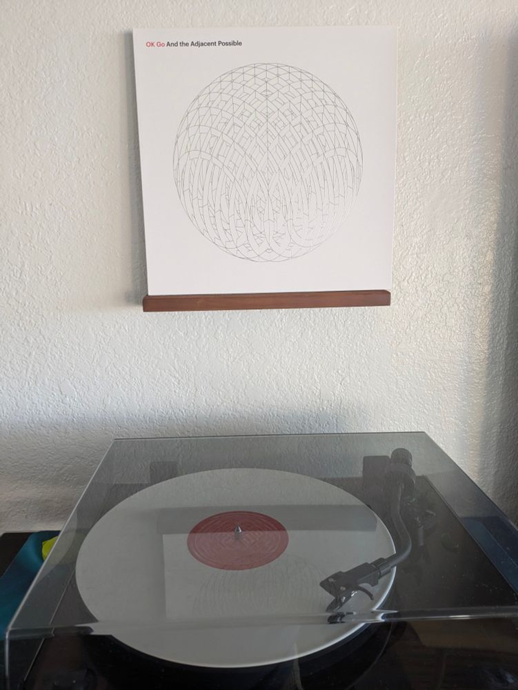 OK Go "And The Adjacent Possible" vinyl playing in a record player with the jacket on a display 