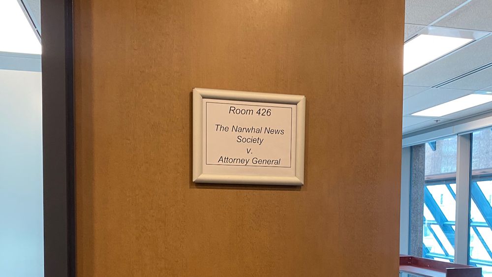 A sign on a brown door reads "Room 426 - The Narwhal News Society v. Attorney General"