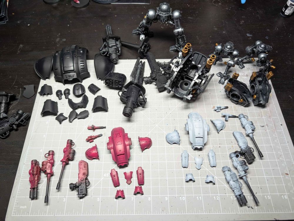 Work in Progress photo of Imperial Knights for Warhammer 40k. They are in sub-assemblies with the large Knight having black armour plates and two smaller Knights with magenta and white plates.