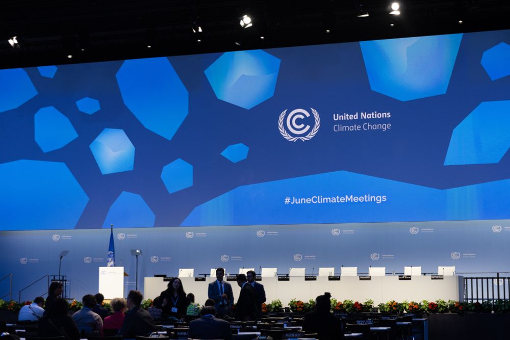 A view of plenary, as it is slowly filling up with delegates. The backdrop of the dais is a mosaic of blue.