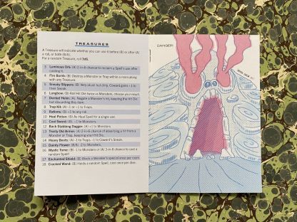 And interior shot of Spirals. The lefthand page is the Treasures table, while the righthand side is a full-page color illustration of a skull-shaped cave with threatening red light and/or fog spilling out of its eyes and mouth