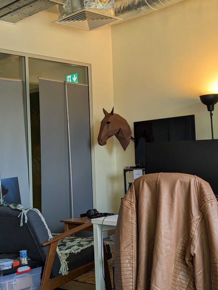 A papercrafted horse head mounted on an office wall