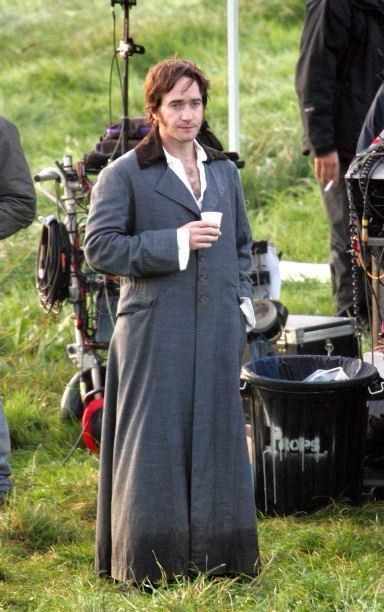 Matthew McFadyen as Mr Darcy standing in his misty walk outfit, holding cup and looking tired 