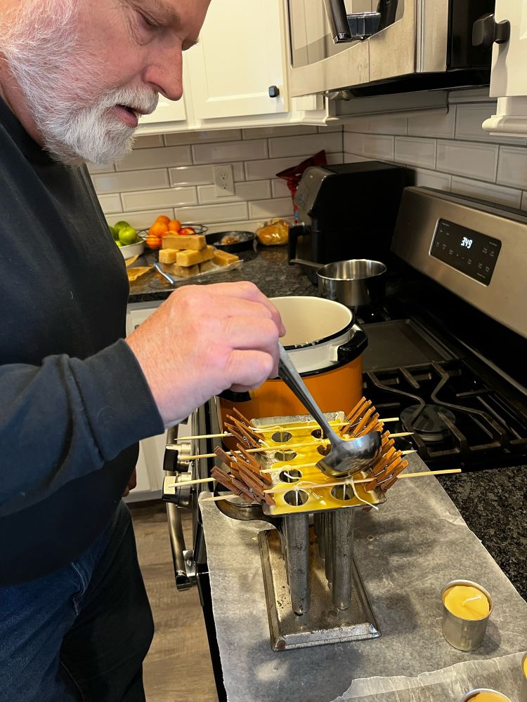 Pa pouring melted beeswax into tin molds