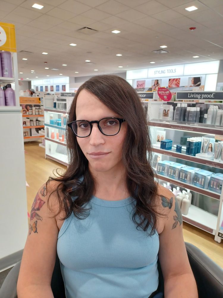 Sitting in a chair at an Ulta beauty salon after just getting my hair done.  I'm wearing a light blue sleeveless top with my head turned slightly.