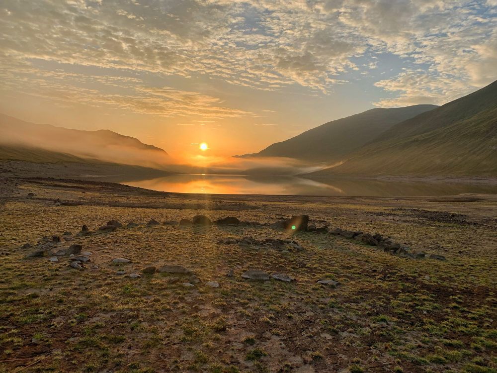 A low circle of stones at the head of a valley with water in the distance. Image is Loch Lungard Hut Circle, Highland. Copyright Glenn Wilks. 