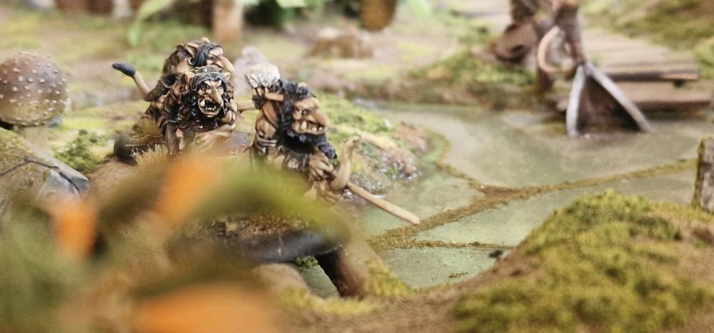three forest trolls sneaking across a swamp bridge of fallen logs.