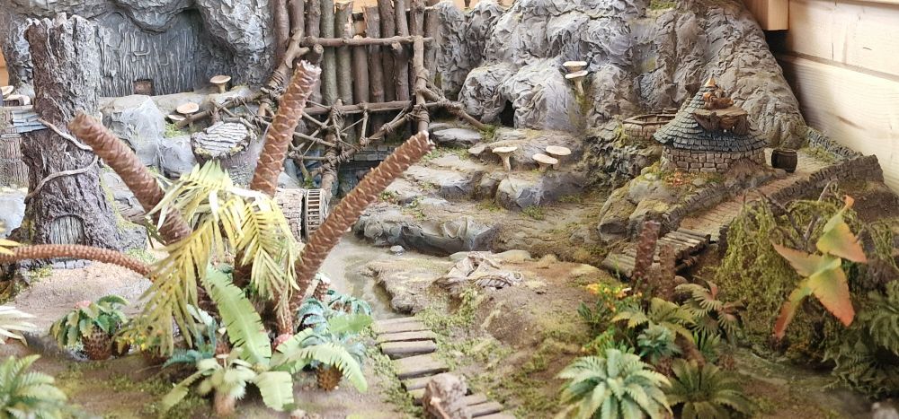 View from one end of a gaming table  featuring a small village around the base of an artificial dam in a mountainside.