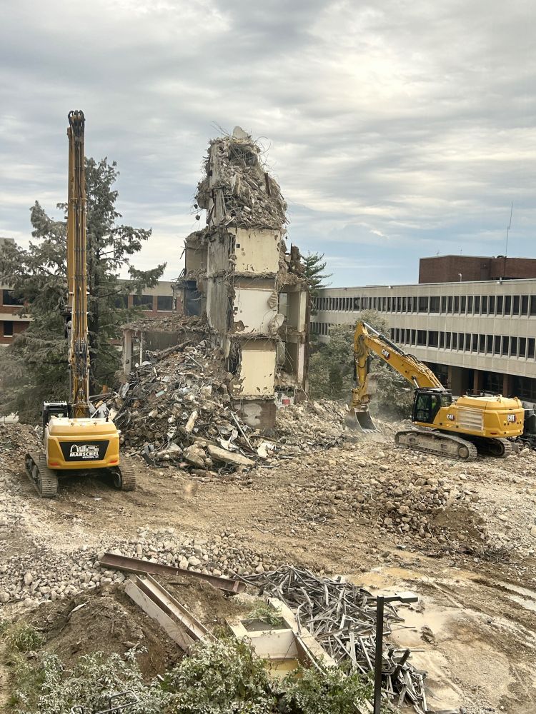 A concrete tower being torn down by excavators