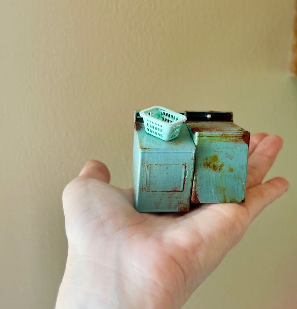 A rusty and dirty washer and dryer set with a tiny laundry basket on top of the dryer