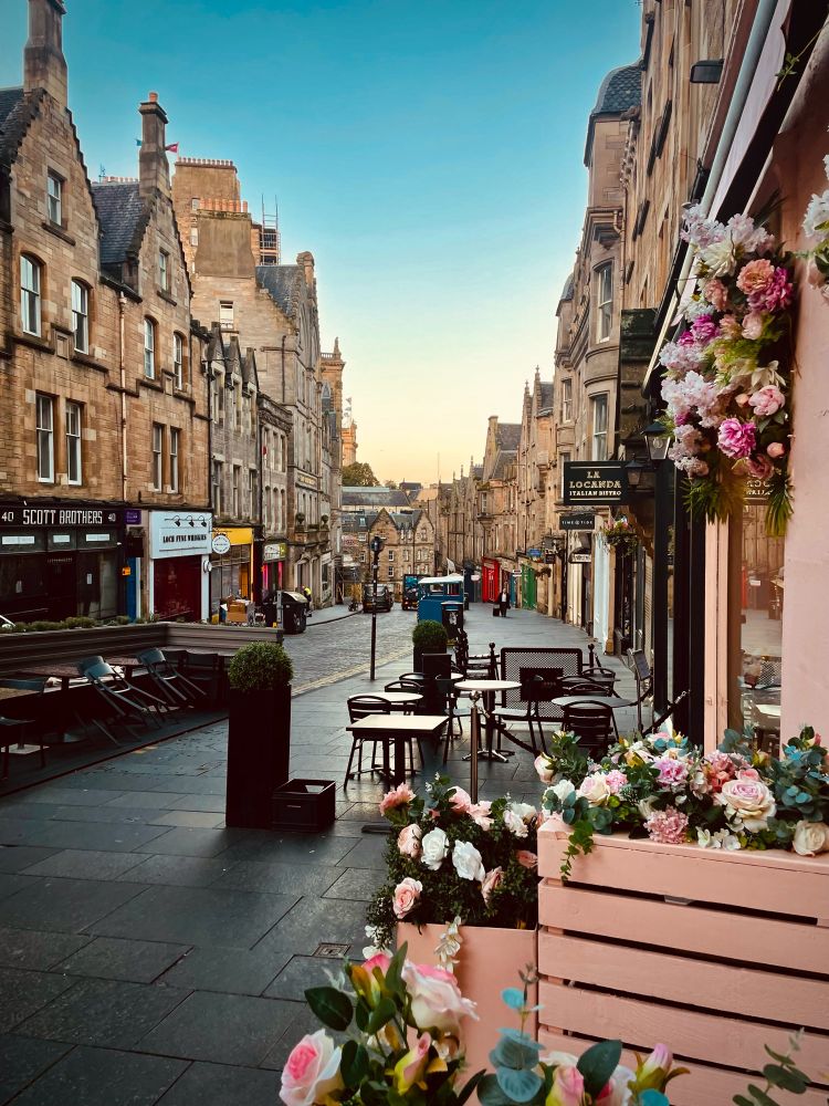 Edinburgh, Cockburn Street im Oktober 2021. Die Sonne geht langsam unter. Rechts im Bild die blumengeschmückte rosa Fassade eines Café.