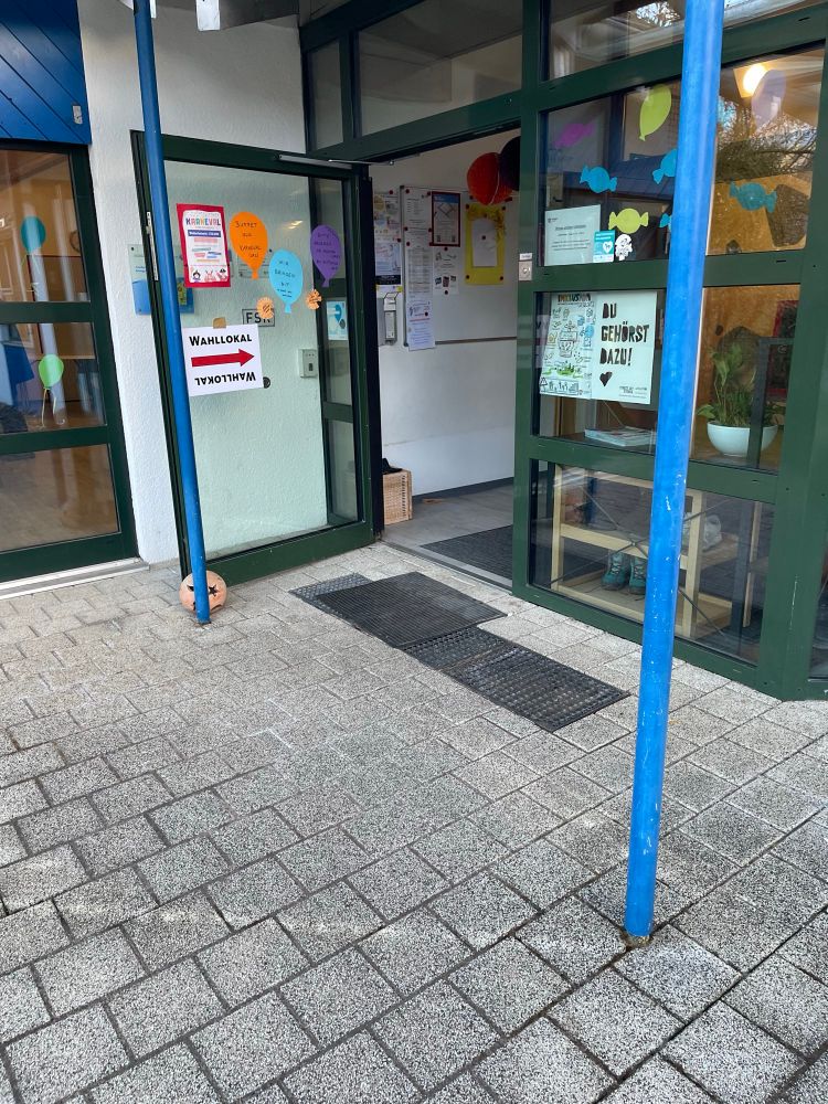 Offene Haustür des als Wahllokal fungierenden Kindergartens mit Wegweiser „Wahllokal“