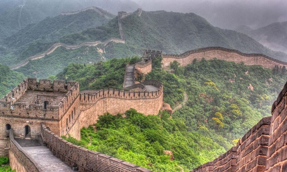 Photo montrant une partie de la Muraille de Chine, zigzaguant entre des collines verdoyantes