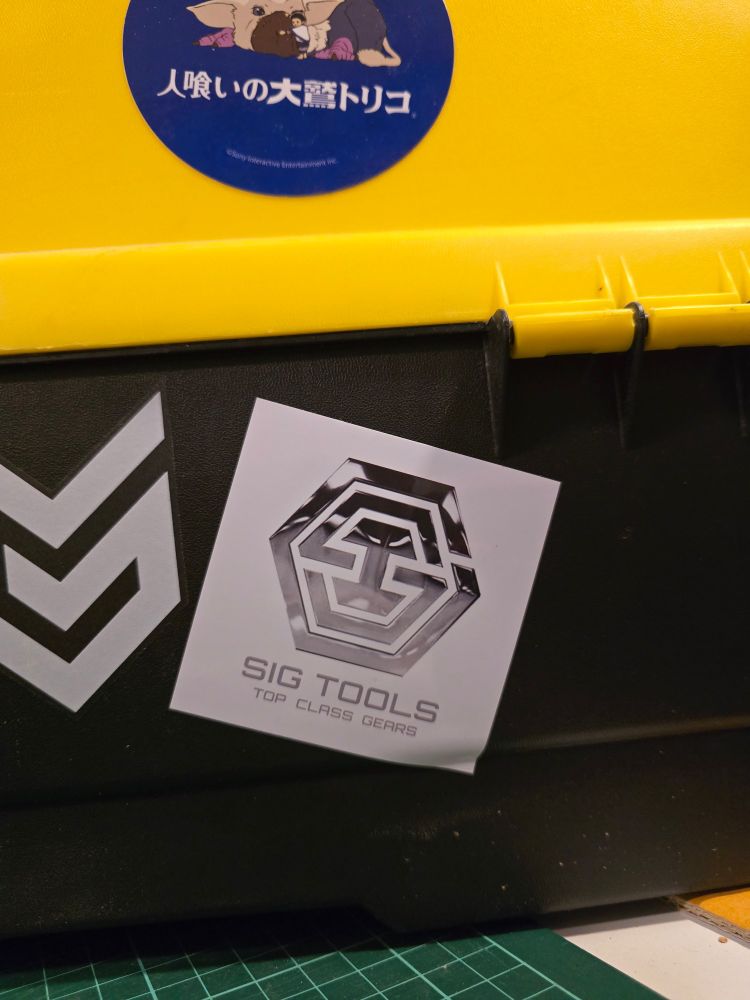 A sticker the SIG TOOLS amongst some others on a black and yellow toolbox.