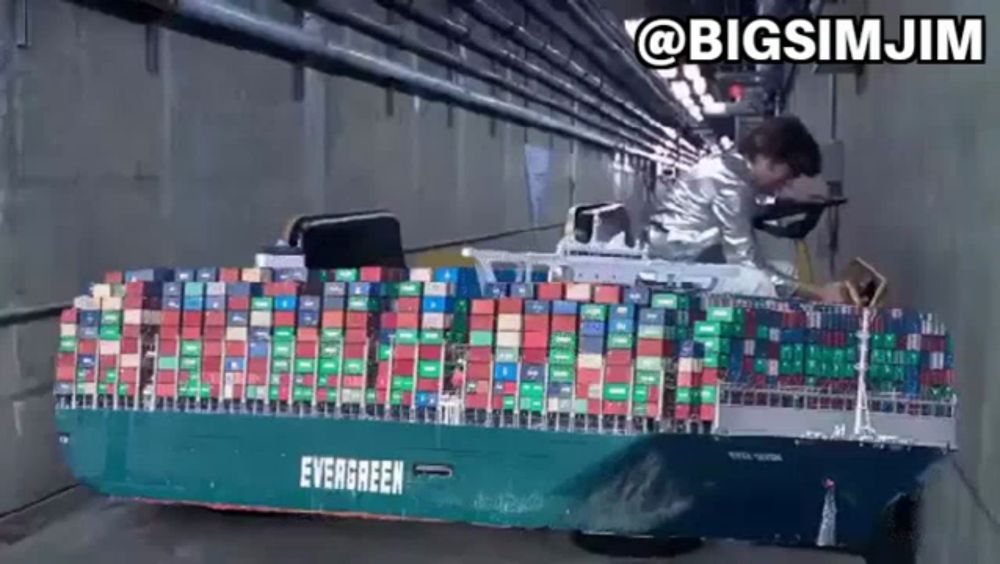 a large evergreen container ship is pulled by a man