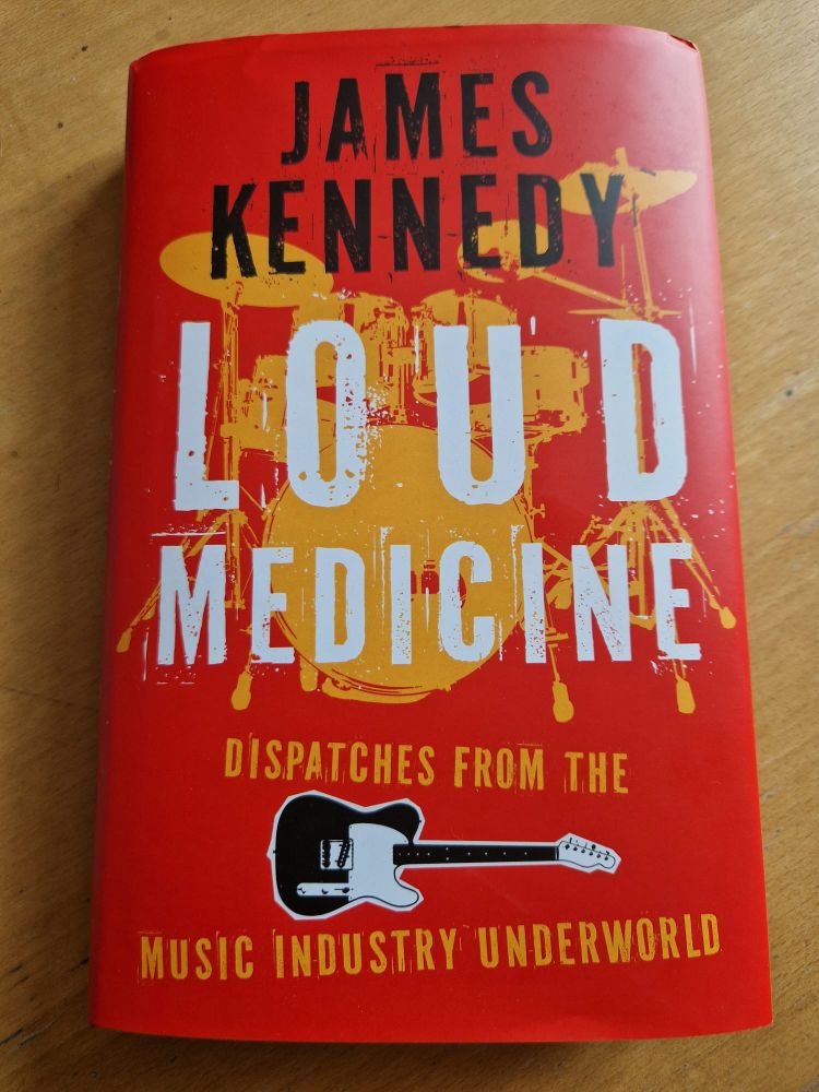 Picture of hardback copy of James Kennedy's new book 'Loud Medicine' featuring pictures of a drum kit and guitar.